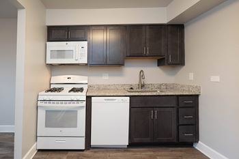 Kitchen with dark cabinets and white appliances at McDonogh Village Apartments & Townhomes, Randallstown